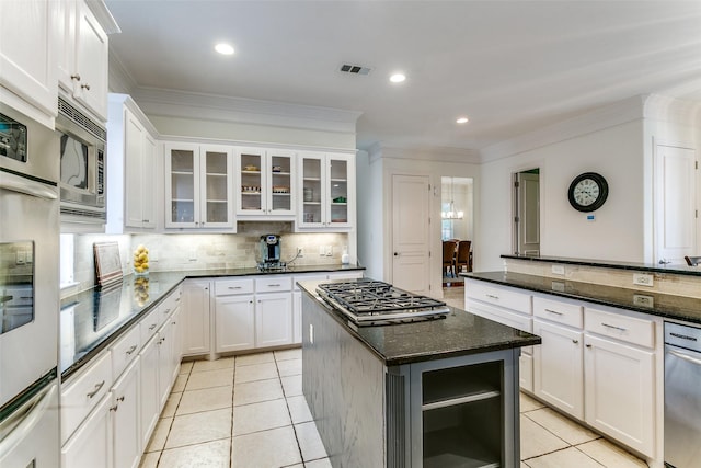 kitchen with appliances with stainless steel finishes, decorative backsplash, light tile patterned floors, a kitchen island, and visible vents
