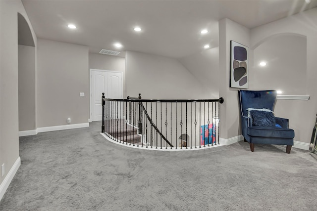 sitting room with carpet flooring, baseboards, visible vents, and an upstairs landing