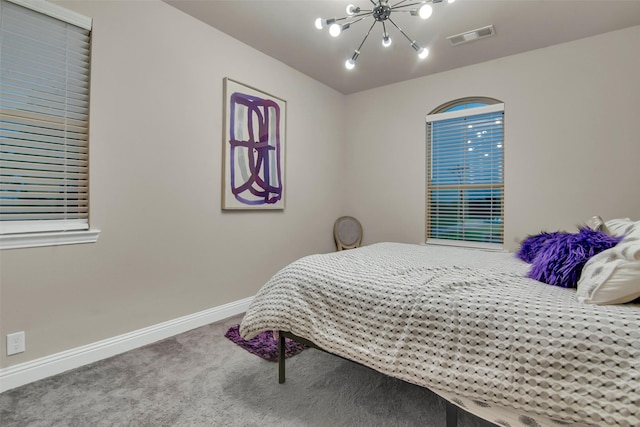 carpeted bedroom with baseboards, a chandelier, and visible vents