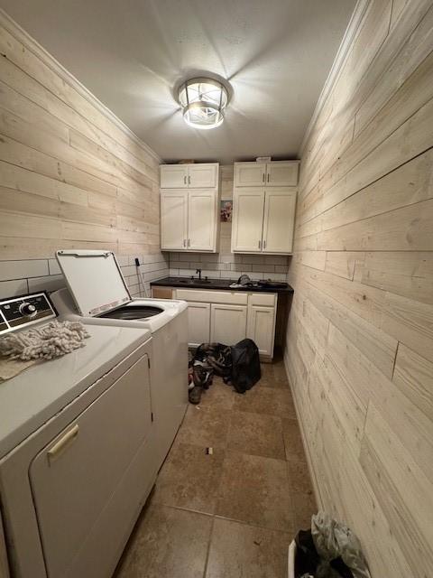 405 E Lee St, Rotan, TX 79546 - laundry area with crown molding, wood walls, cabinet space, and washing machine and clothes dryer