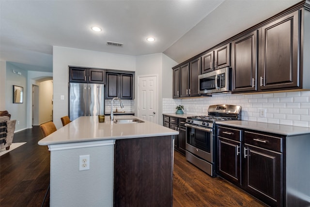 1809 6th St, Argyle, TX 76226 - kitchen featuring stainless steel appliances, a sink, arched walkways, light countertops, and dark wood finished floors