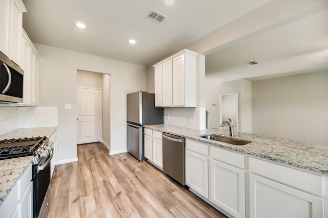 kitchen with visible vents, light wood-type flooring, white cabinets, a sink, and stainless steel appliances