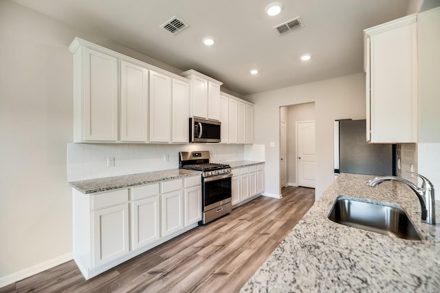 kitchen featuring visible vents, a sink, baseboards, and appliances with stainless steel finishes