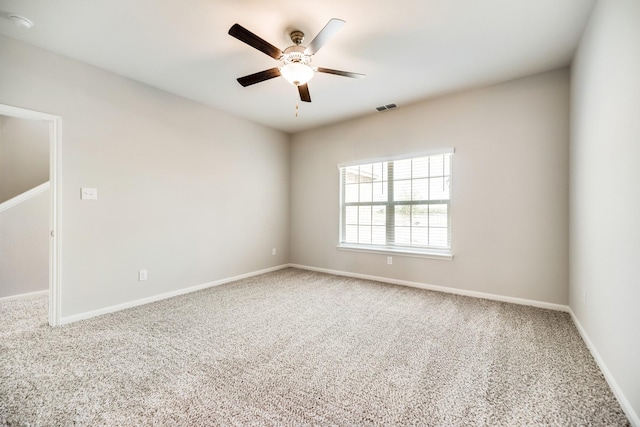 carpeted spare room featuring visible vents, a ceiling fan, and baseboards