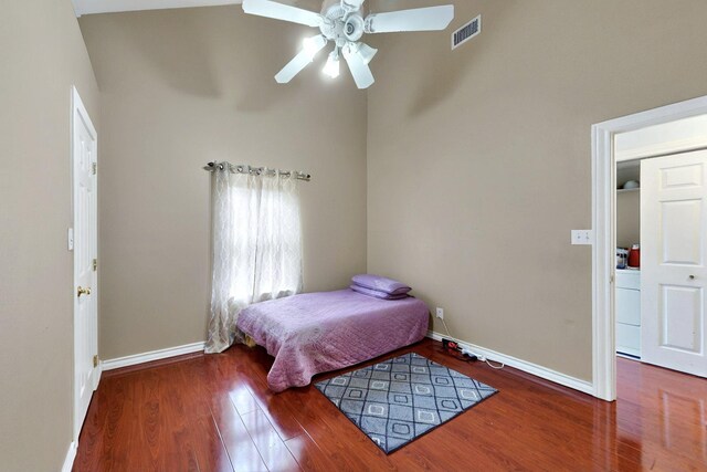 bedroom featuring wood finished floors, baseboards, a ceiling fan, and a high ceiling