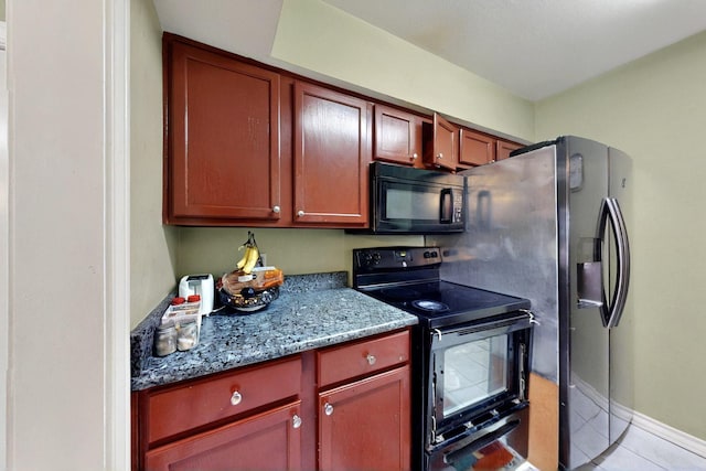 kitchen with black microwave, range with electric cooktop, light tile patterned flooring, light stone counters, and baseboards