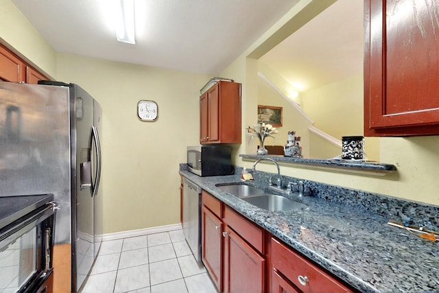 kitchen featuring stainless steel appliances, a sink, reddish brown cabinets, baseboards, and light tile patterned floors