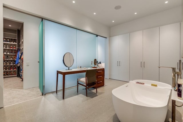 interior space with recessed lighting, a freestanding tub, and a spacious closet