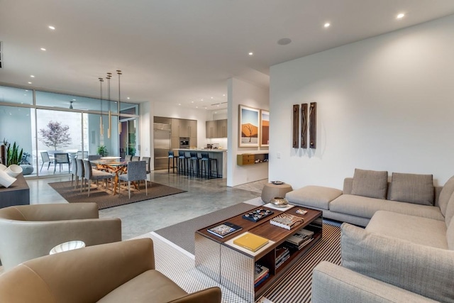 living room featuring recessed lighting, a wall of windows, and finished concrete floors