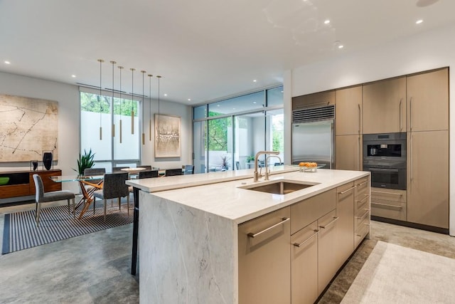 kitchen featuring an island with sink, modern cabinets, recessed lighting, built in fridge, and a sink