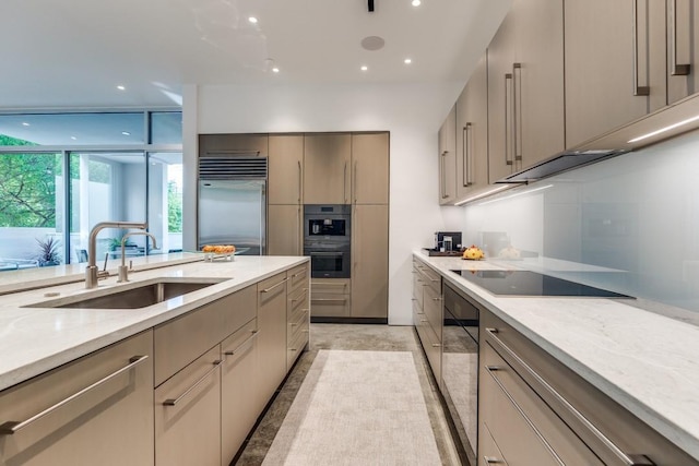 kitchen featuring modern cabinets, light stone countertops, a sink, black appliances, and recessed lighting
