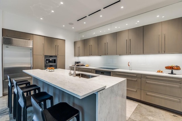 kitchen featuring appliances with stainless steel finishes, a sink, a breakfast bar area, a center island with sink, and modern cabinets