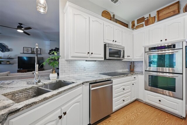 kitchen featuring stainless steel appliances, light stone countertops, and white cabinetry
