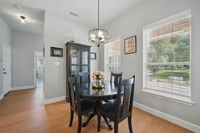 dining space featuring light wood-style flooring, healthy amount of natural light, and a chandelier