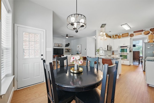 dining area with a chandelier, light wood-style flooring, and ceiling fan