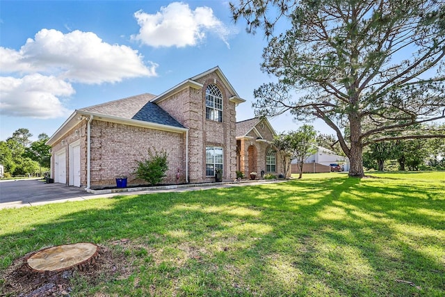 traditional home with brick siding, a front yard, an attached garage, asphalt driveway, and a shingled roof
