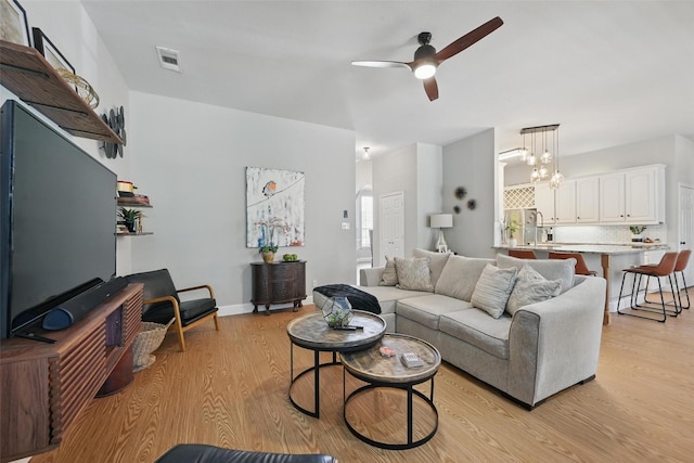 living room featuring ceiling fan, light wood-style flooring, and a chandelier