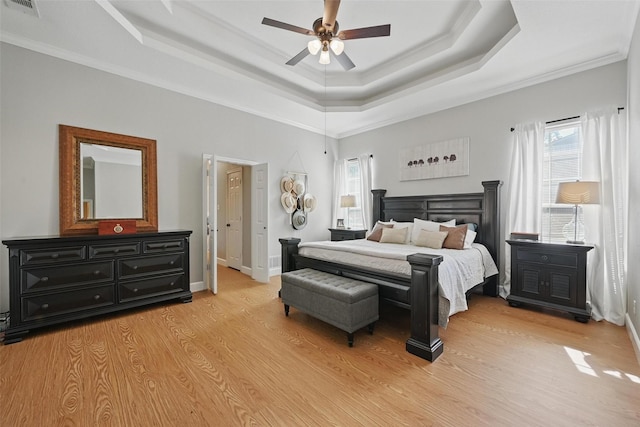 bedroom with a tray ceiling, light wood finished floors, baseboards, ornamental molding, and ceiling fan