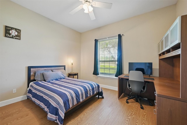 bedroom featuring an office area, wood finished floors, baseboards, ceiling fan, and vaulted ceiling