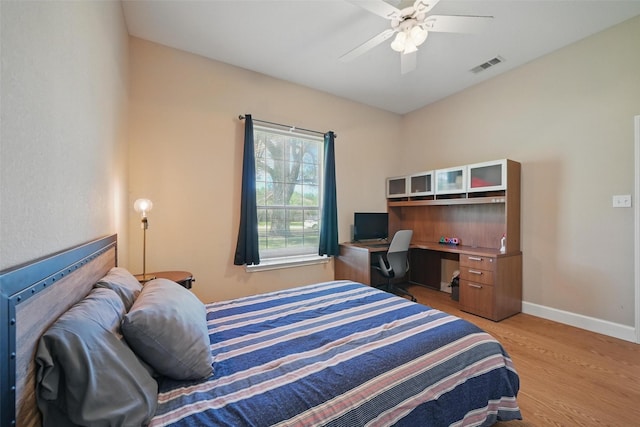 bedroom with light wood finished floors, baseboards, a ceiling fan, and a desk