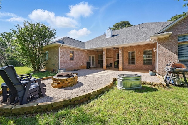 rear view of house with a fire pit, a patio, brick siding, a yard, and a chimney