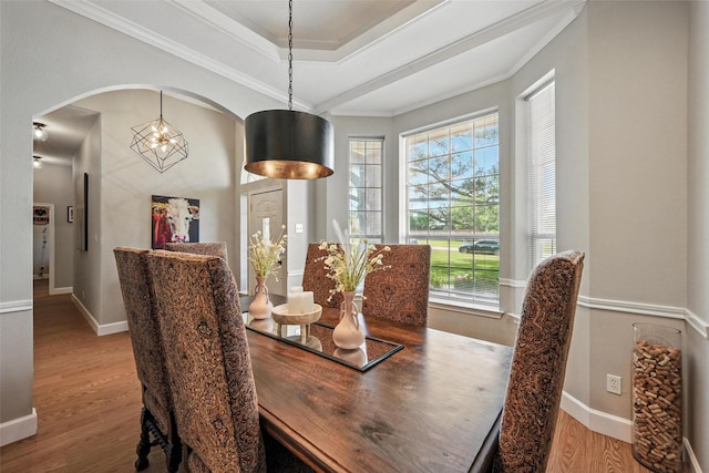 dining room with wood finished floors, arched walkways, crown molding, baseboards, and a chandelier