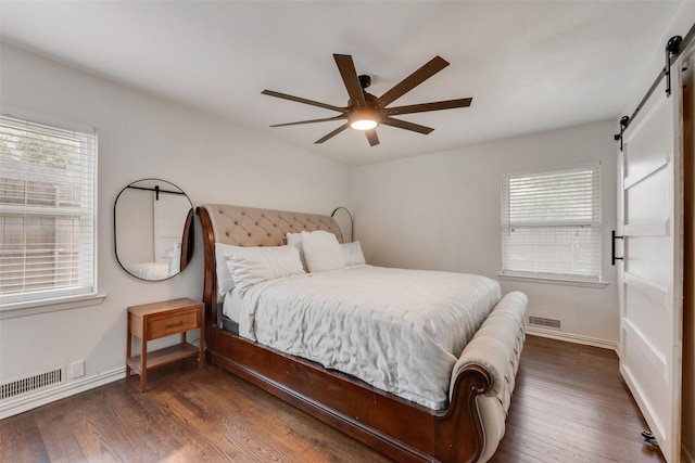 bedroom featuring multiple windows, dark wood-style floors, a barn door, and visible vents