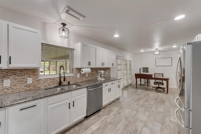 kitchen featuring backsplash, stainless steel appliances, white cabinetry, and a sink