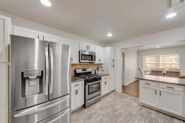 kitchen featuring stone counters, decorative backsplash, white cabinets, and stainless steel appliances