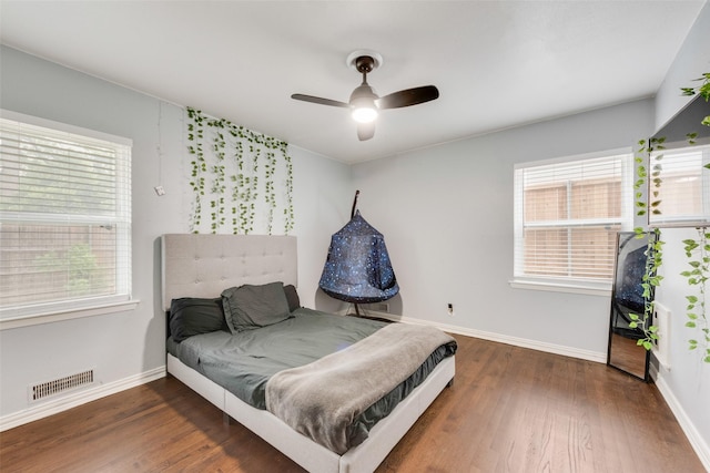 bedroom with baseboards, multiple windows, wood finished floors, and visible vents