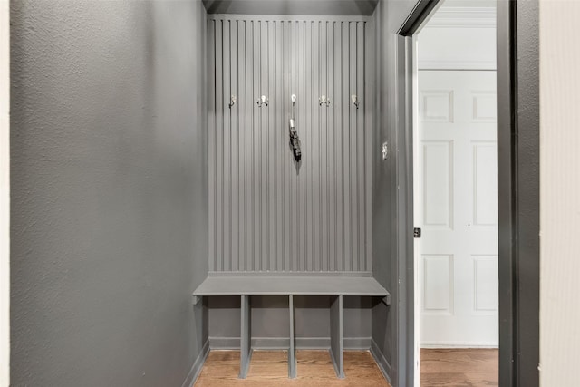mudroom featuring baseboards, a textured wall, and wood finished floors