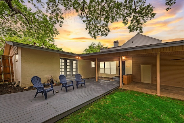 back of property featuring brick siding, a chimney, french doors, and a deck