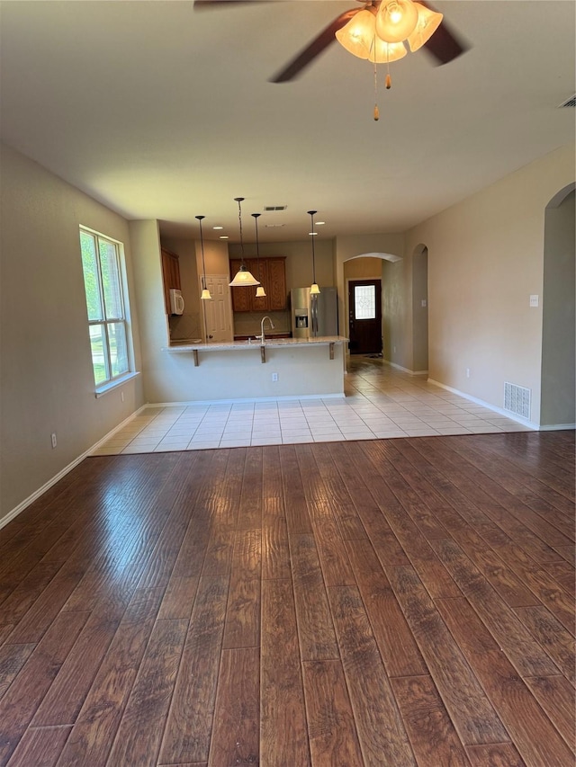406 Fisherman Trl, Melissa, TX 75454 - unfurnished living room with visible vents, a sink, arched walkways, a ceiling fan, and light wood-style flooring