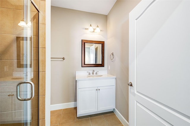 bathroom featuring vanity, baseboards, tile patterned flooring, and a stall shower