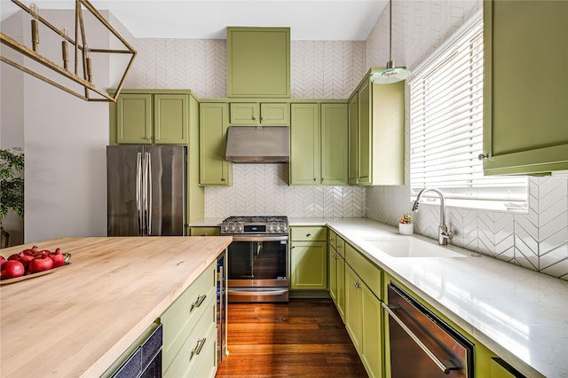 kitchen featuring dark wood-style floors, under cabinet range hood, a sink, appliances with stainless steel finishes, and green cabinets