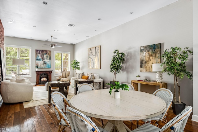 dining room featuring visible vents, a lit fireplace, recessed lighting, a ceiling fan, and dark wood finished floors