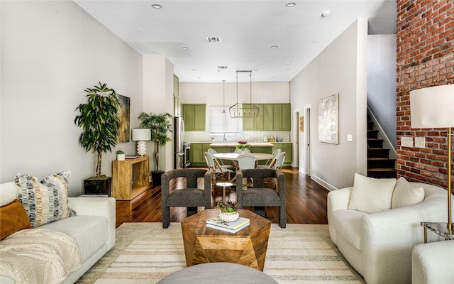 living room featuring stairs, brick wall, visible vents, and light wood-style floors