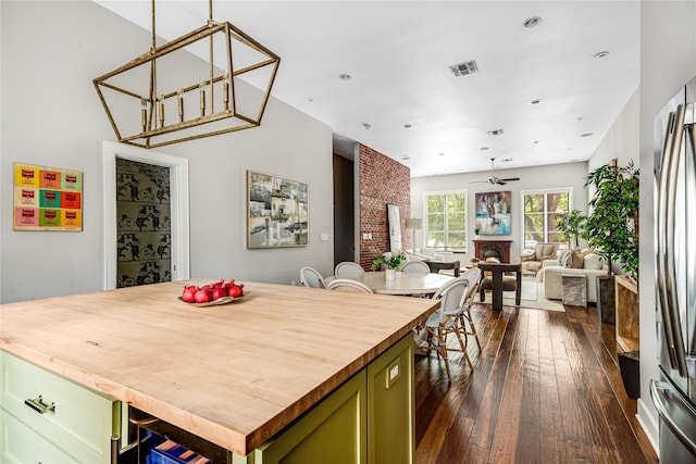 kitchen featuring dark wood-style flooring, green cabinetry, ceiling fan, butcher block countertops, and visible vents