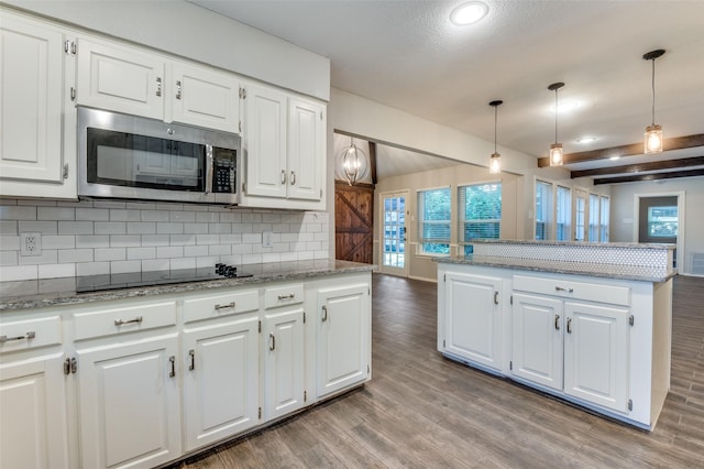kitchen featuring black electric stovetop, light wood-style flooring, tasteful backsplash, and stainless steel microwave