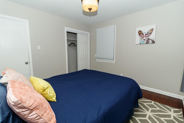 bedroom with wood finished floors, a closet, and baseboards