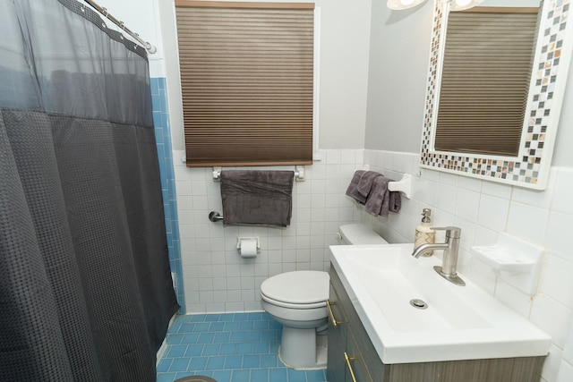 bathroom with tile patterned floors, toilet, wainscoting, tile walls, and a shower with curtain
