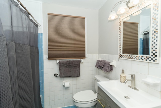 bathroom with vanity, toilet, tile walls, a shower with shower curtain, and a wainscoted wall