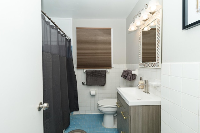 bathroom with tile patterned floors, toilet, tile walls, vanity, and wainscoting