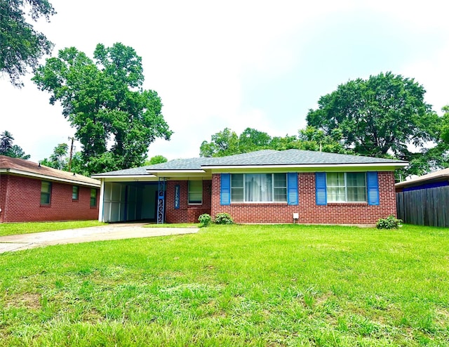 ranch-style home featuring concrete driveway, an attached carport, a front yard, and brick siding
