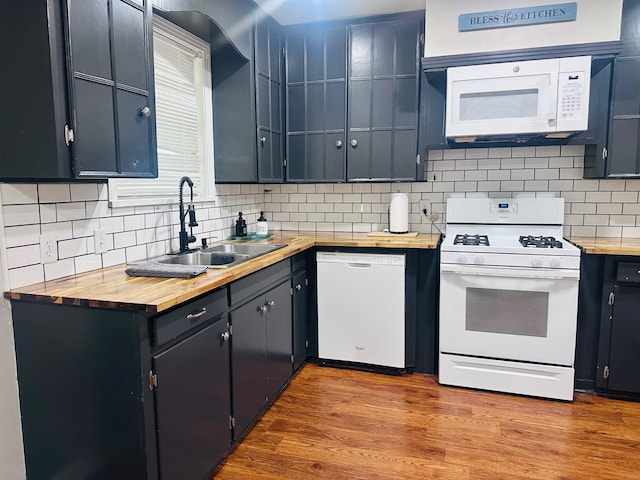 kitchen featuring white appliances, a sink, butcher block counters, and decorative backsplash