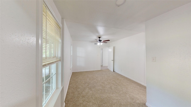 empty room featuring a ceiling fan, baseboards, and carpet