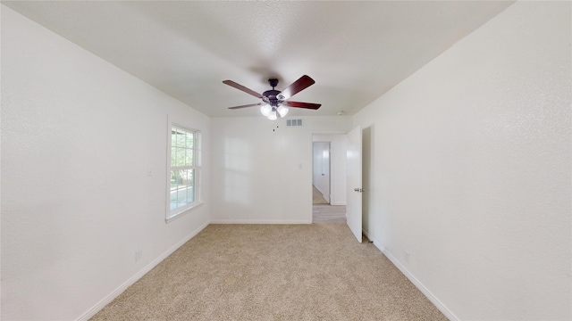 empty room with baseboards, a ceiling fan, light colored carpet, and visible vents