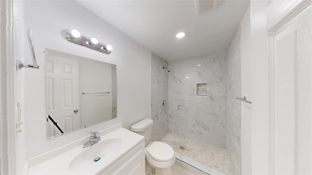 bathroom featuring toilet, visible vents, a marble finish shower, and vanity
