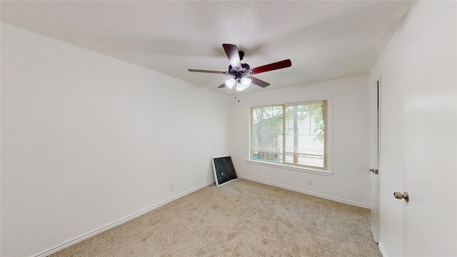 spare room with baseboards, ceiling fan, and light colored carpet