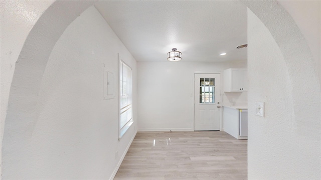 unfurnished dining area with a textured ceiling, visible vents, light wood-type flooring, baseboards, and recessed lighting